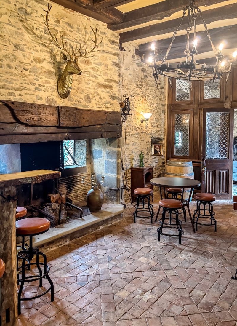 Rustic stone lounge with a large fireplace at Chateau Eyparsac
