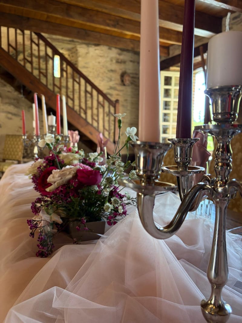 Floral centrepiece on a dressed wedding table beside a window at Chateau Eyparsac