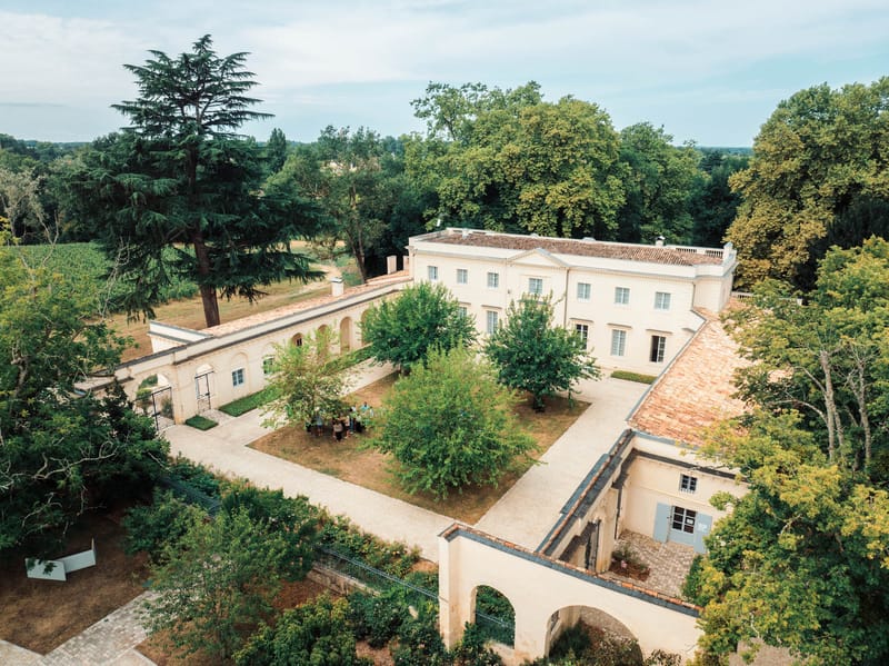 Aerial view of Chateau de l'Hospital showing the neoclassical facade, arcaded orangery and walled four-hectare park