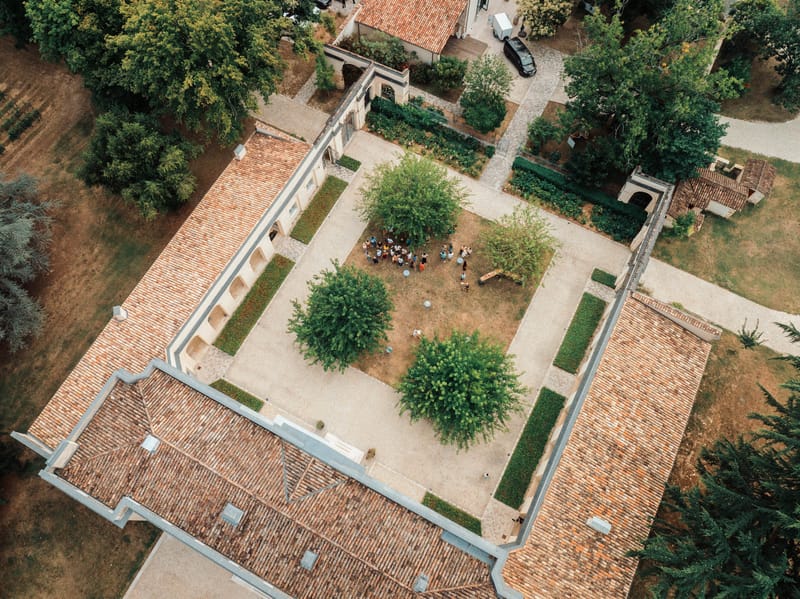 Overhead aerial of Chateau de l'Hospital showing terracotta roof, courtyards and parterre gardens