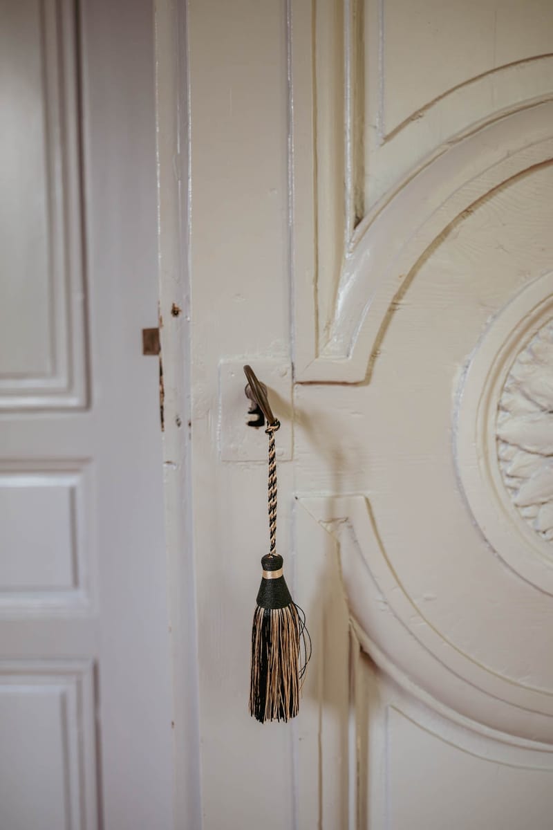 Close-up detail of an antique chateau door at Chateau de l'Hospital with a silk tassel pull
