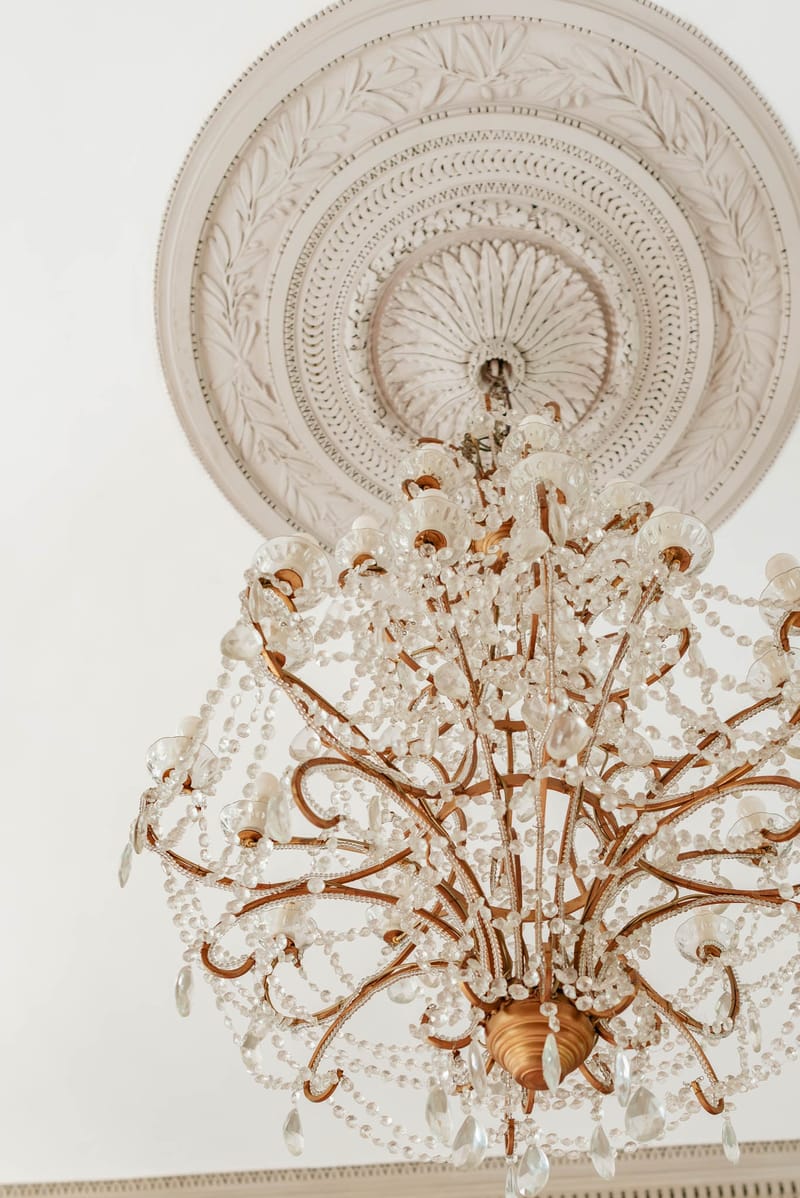 Close-up of a crystal chandelier hanging from an ornate plaster ceiling rosette at Chateau de l'Hospital