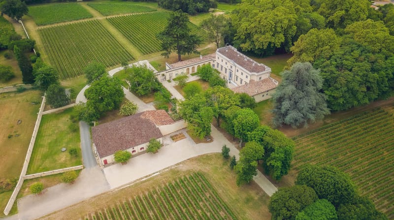 Drone shot of Chateau de l'Hospital vineyards with the driveway and outbuildings converging at the chateau