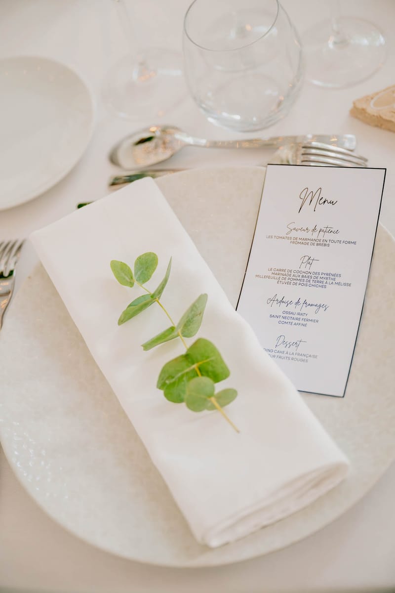 Close-up of a menu card on a folded linen napkin with a sprig of eucalyptus at Chateau de l'Hospital