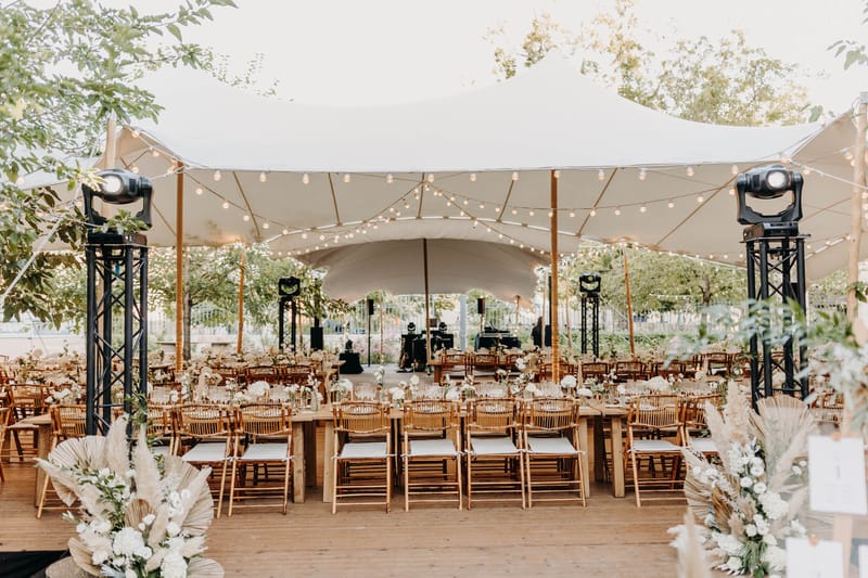 Reception stretch tent at Chateau de l'Hospital with stage, dance floor and guests dining under festoon lights