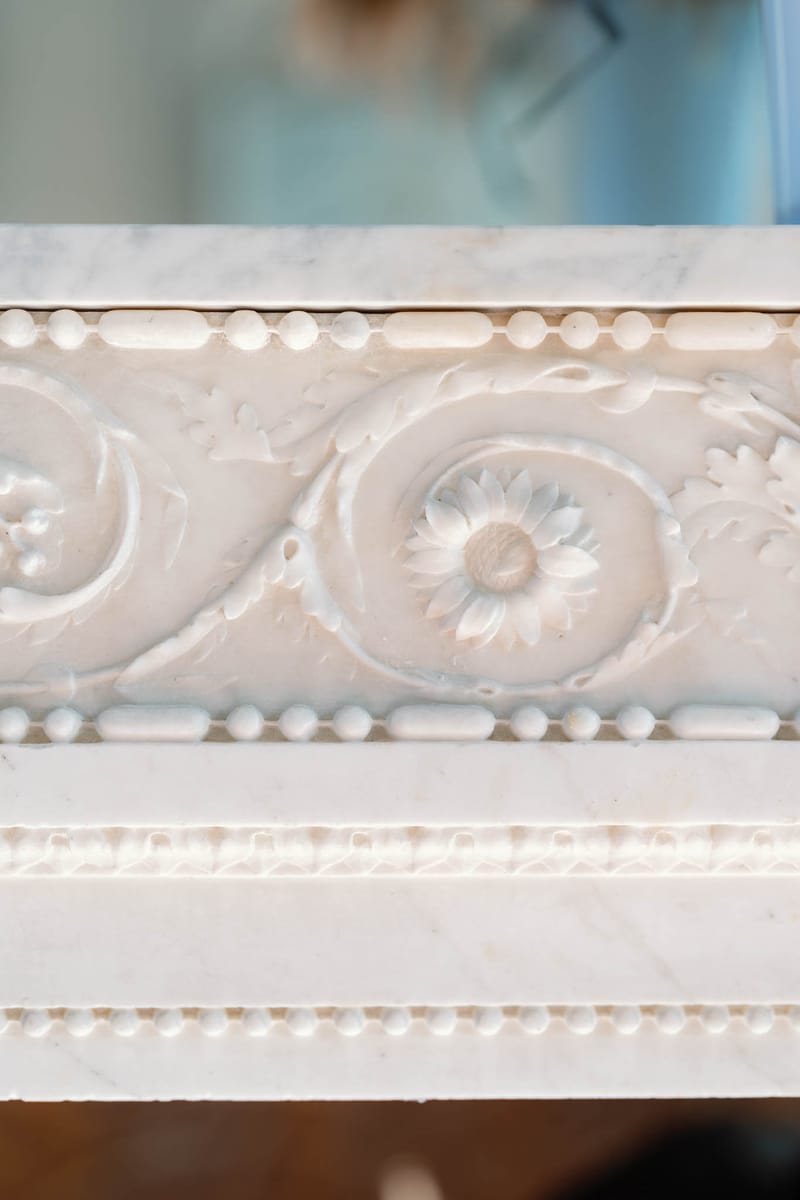 Close-up of a carved white marble fireplace frieze at Château de l'Hospital