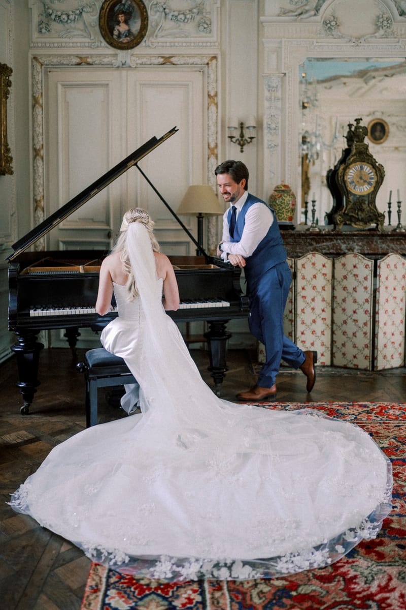 The panelled salon with a grand piano, a mantel clock and parquet floors