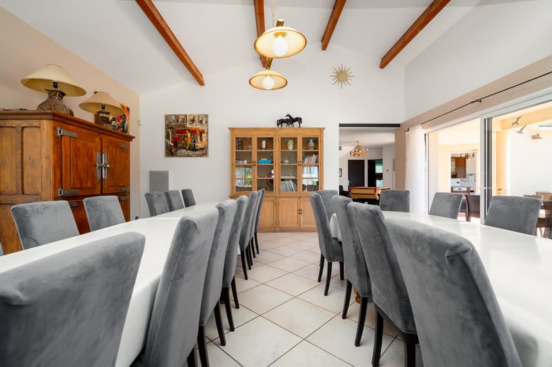 The dining room of one of the private villas, set with long tables and grey chairs beside a wooden dresser and display cabinet.
