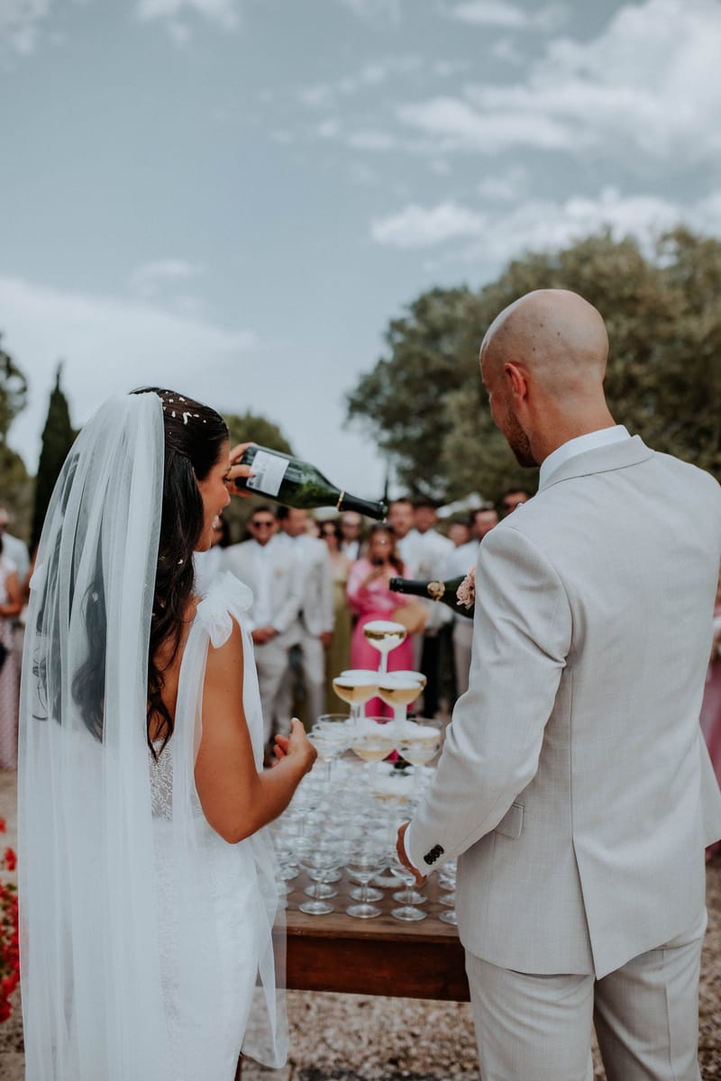 The couple pour champagne over a tower of coupes as their guests look on