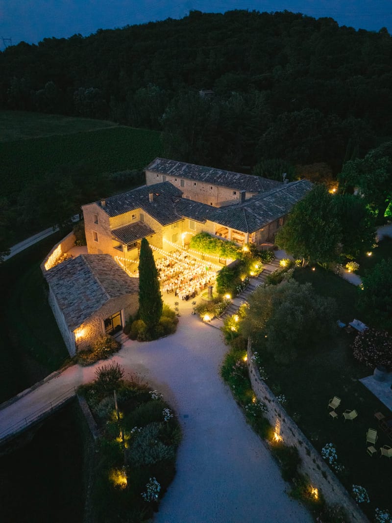 Aerial night view of Domaine de Valbonne reception dinner with festoon lighting and stone buildings