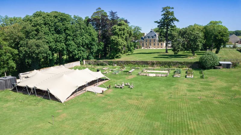 Stretch tent set up on the lawn at Domaine Le Mezo with the chateau and walled kitchen garden behind