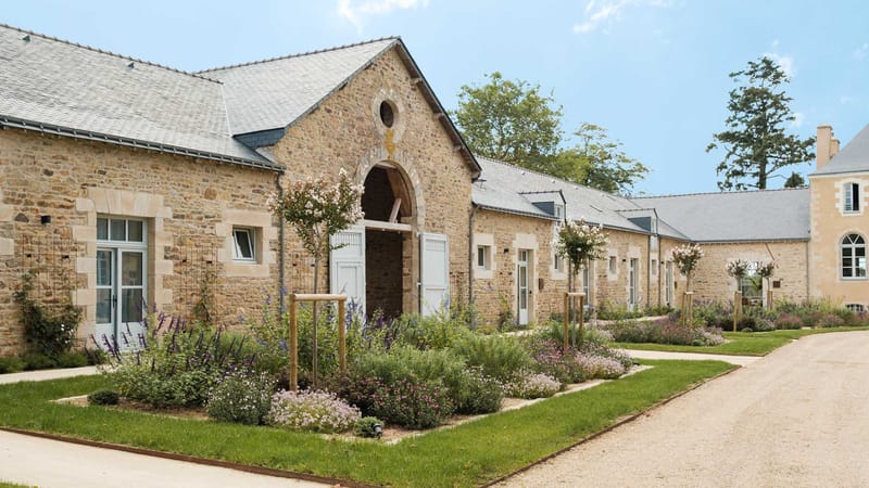 Restored stone outbuildings at Domaine Le Mezo with an arched entrance and planted borders
