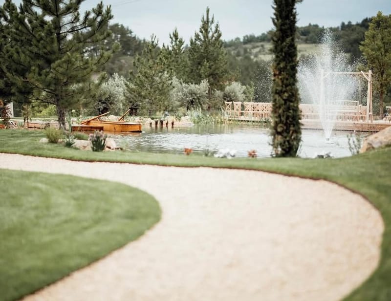 Gravel path curving through the lawns to the lake and fountain in the grounds of Le Mas des Cinq Fontaines.