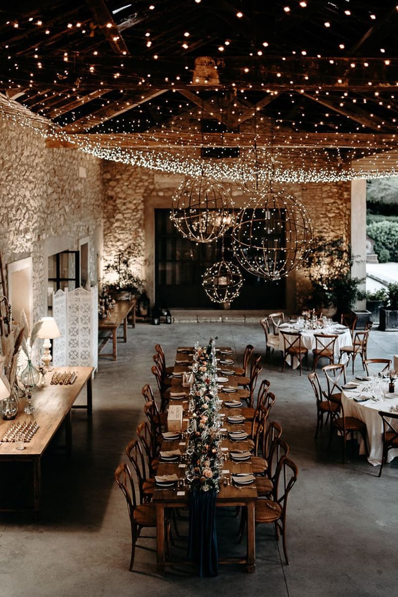 Mas D'Arvieux rustic stone reception hall with string light canopy and wooden farm tables