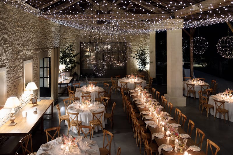 Mas D'Arvieux stone barn reception lit with string lights and orb chandeliers at night