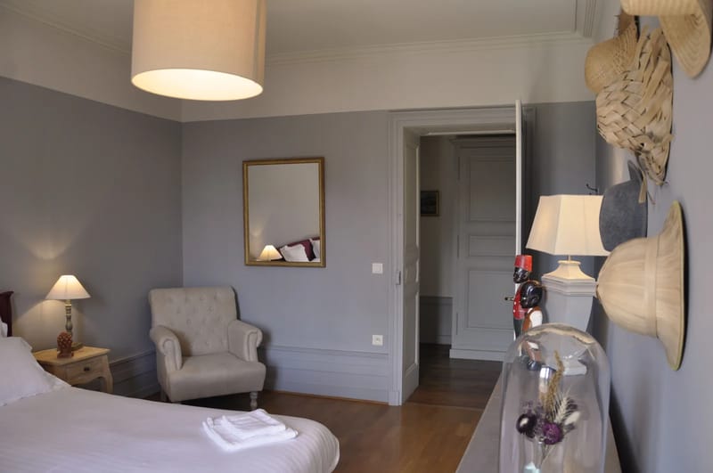 Bedroom suite at Domaine de Vavril with grey walls and a vintage hat display