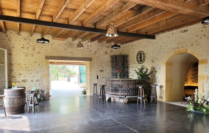 Stone reception barn at Domaine de Vavril with a wine-barrel bar and exposed beams