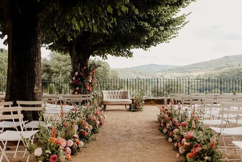 Outdoor ceremony terrace lined with pink and peach flowers at Domaine de Vavril, overlooking the vineyard hills