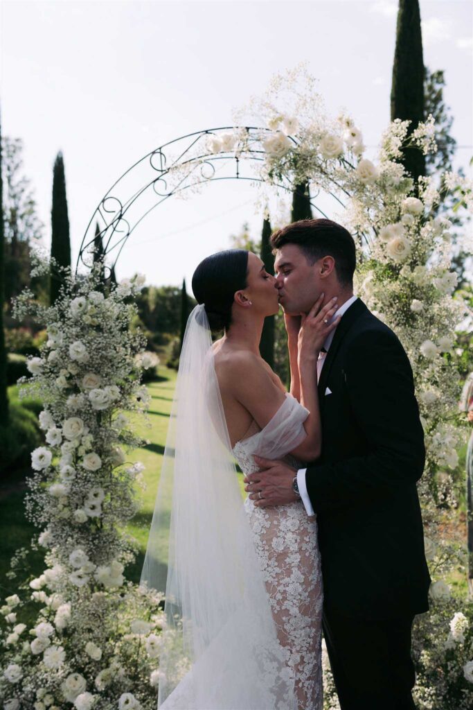 saint eusebe ayata bride groom kissing arch white flower background