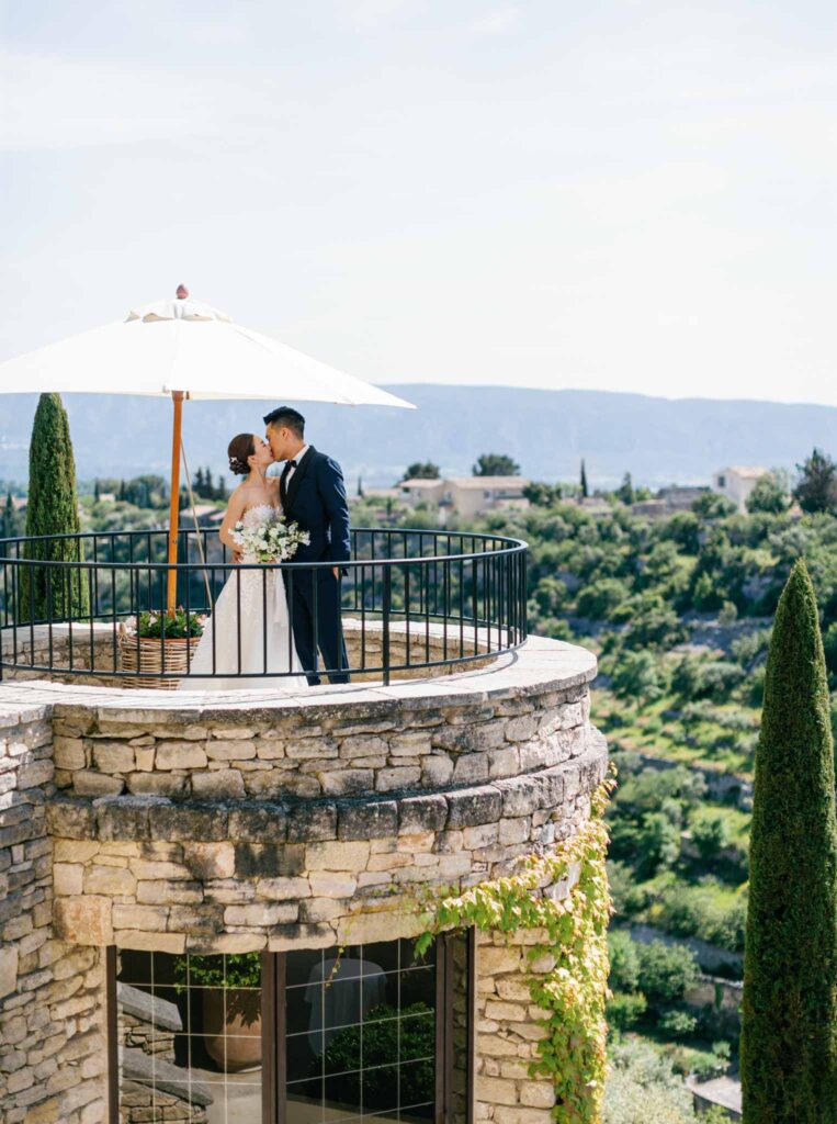 Bastide de Gorde Despinoy bride groom kissing under white umbrella top building