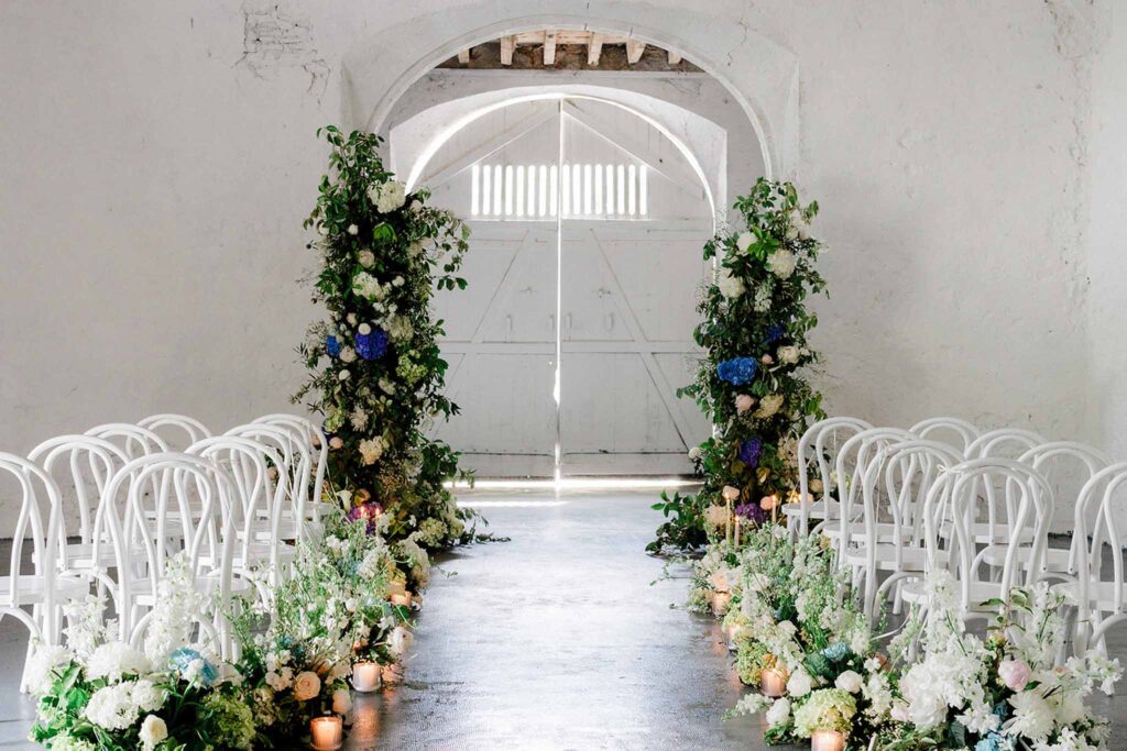 Trieux M.Mann ceremony area white chairs arch flower