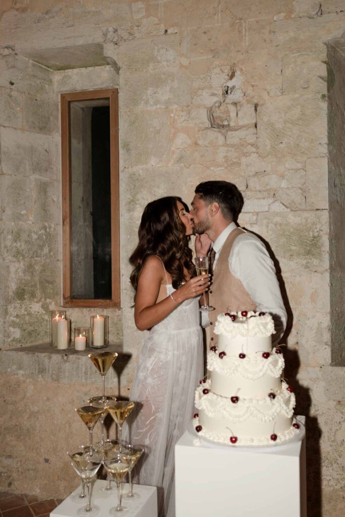 Abbaye Noce Machine bride groom kissing at back of cake and champagne tower