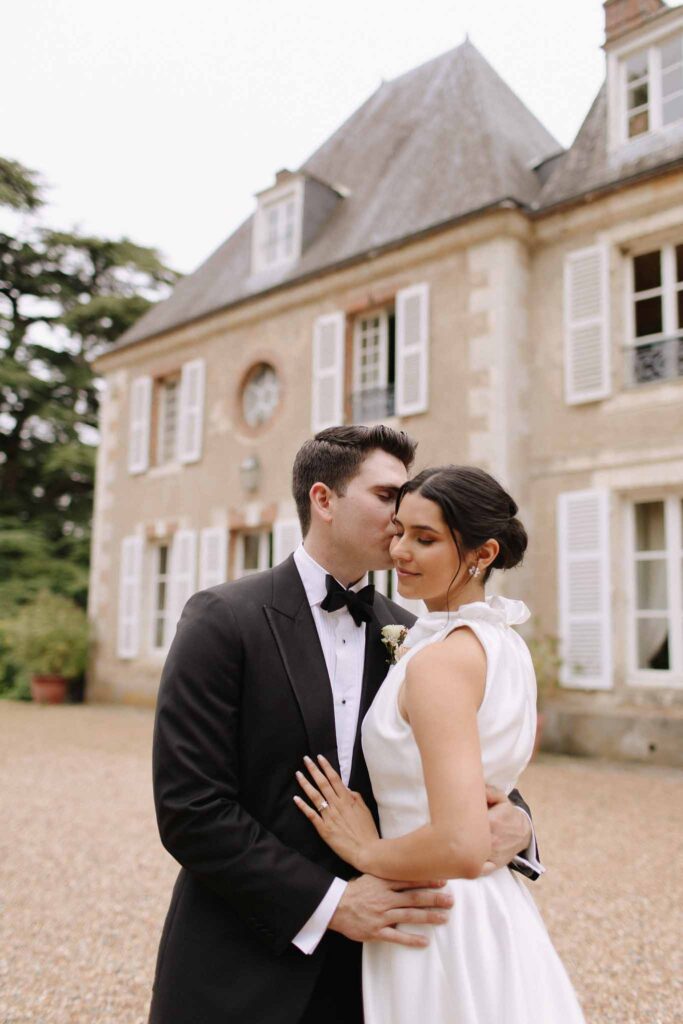 Boutonvillier F.Mary groom kissing brides forehead venue background