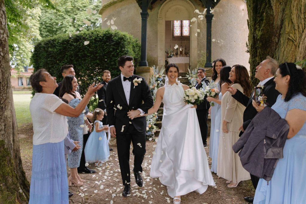 Boutonvillier F.Mary guests toss white petals to couple after ceremony