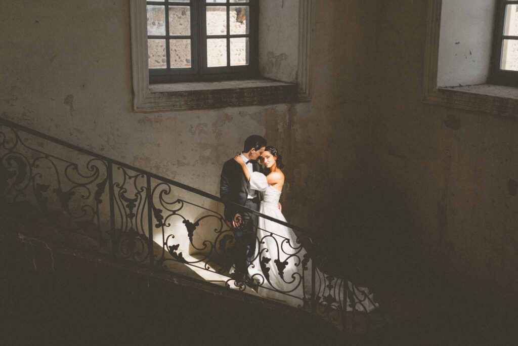 L Amour Fou 3 Maude C Photographe bride hugging groom by old vintage stairs building