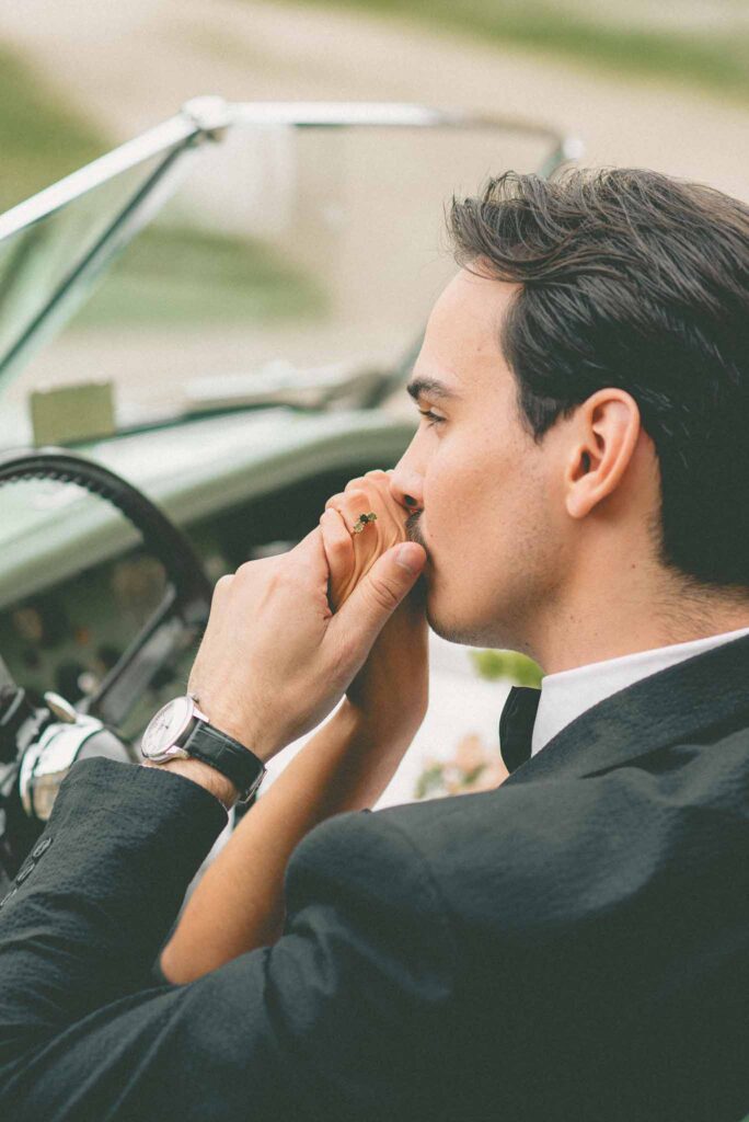 L Amour Fou 3 Maude C Photographe groom kissing brides hands rings vintage car