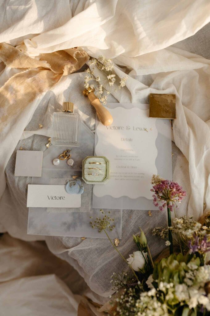 Loire Valley Il Keys flatlay shot invitation rings earrings perfume flower decor white cloth background