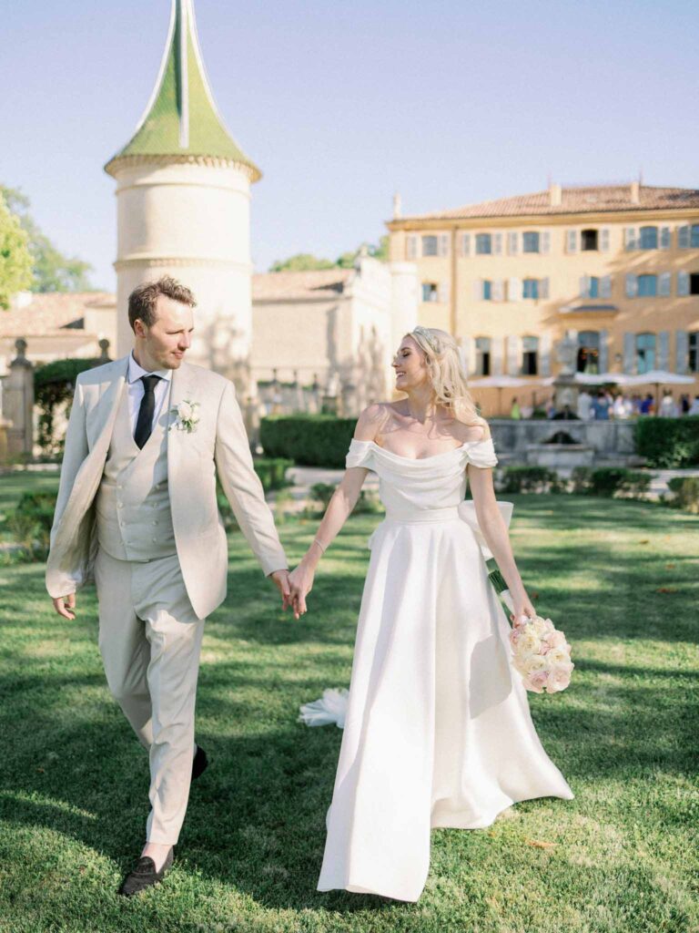 g.dominic m.marechal bride groom walking holding hands chateau background