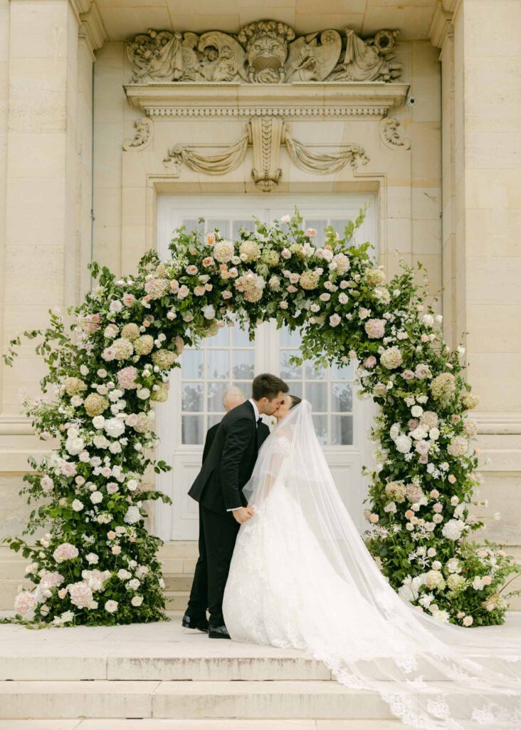 saint martin H.Clark bride groom kissing flower arch background