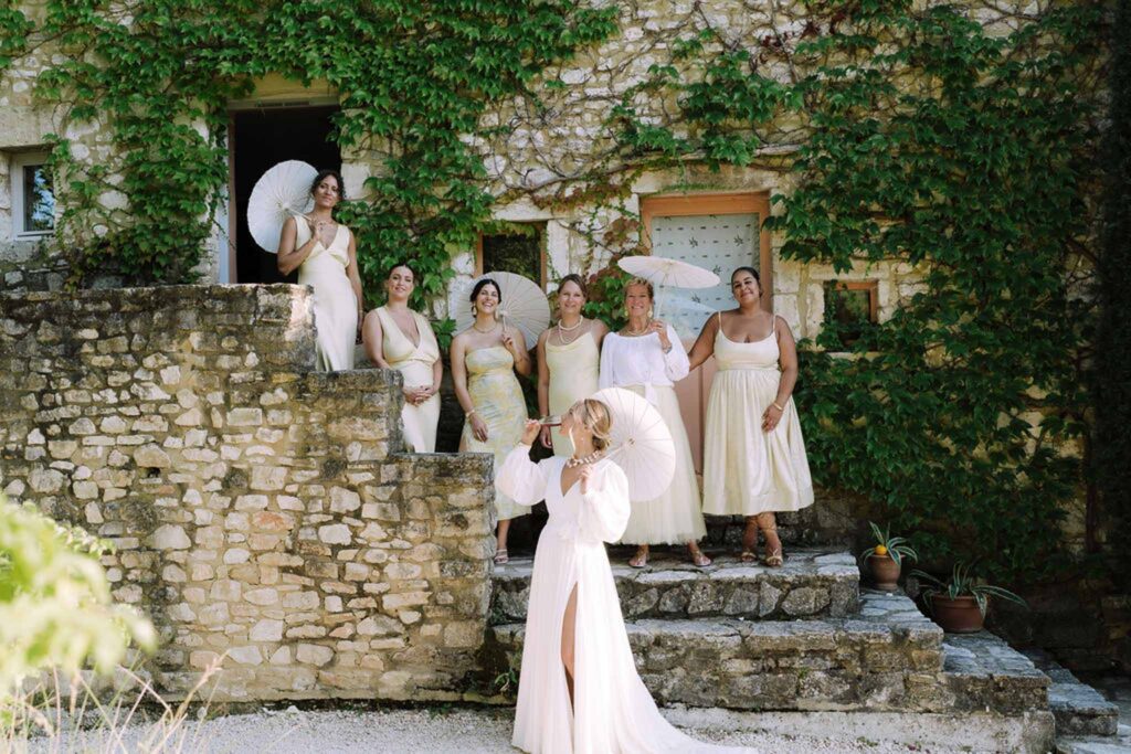 Clos d Hullias Ozaria bride drinking champagne bridesmaids stairs holding white umbrellas