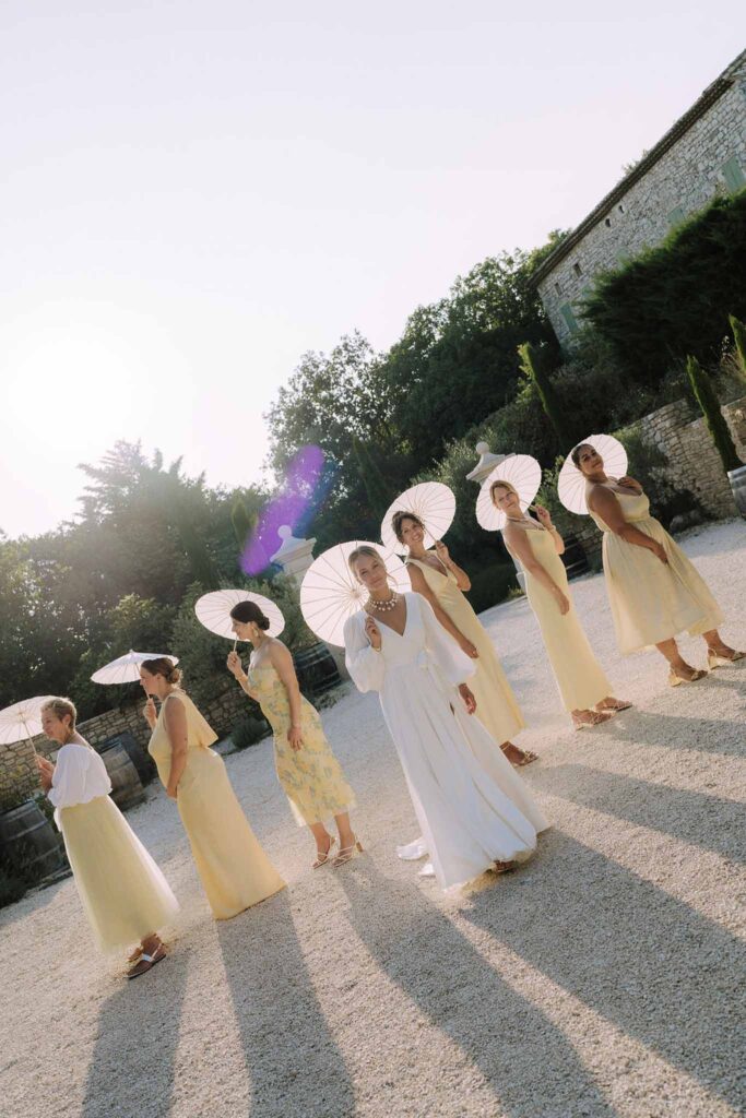 Clos d Hullias Ozaria bride facing camera bridesmaids facing side holding umbrellas sunset