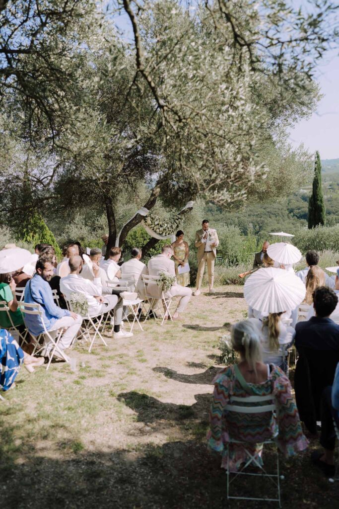 Clos d Hullias Ozaria ceremony proper officiant guests seated under sun trees garden