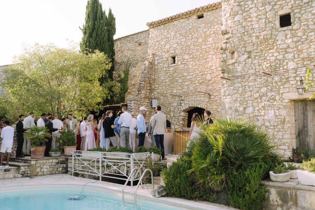 Clos d Hullias Ozaria guests standing cocktail area pool brick wall background trees green