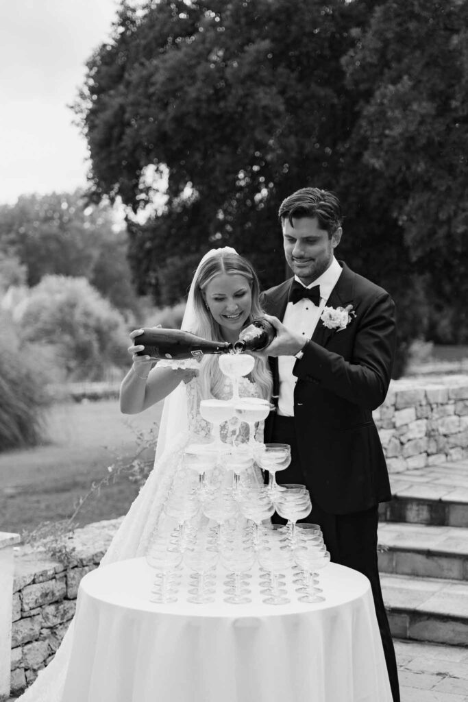 lesCrostes Ingrid bride groom pouring wine champagne glass tower black white photo