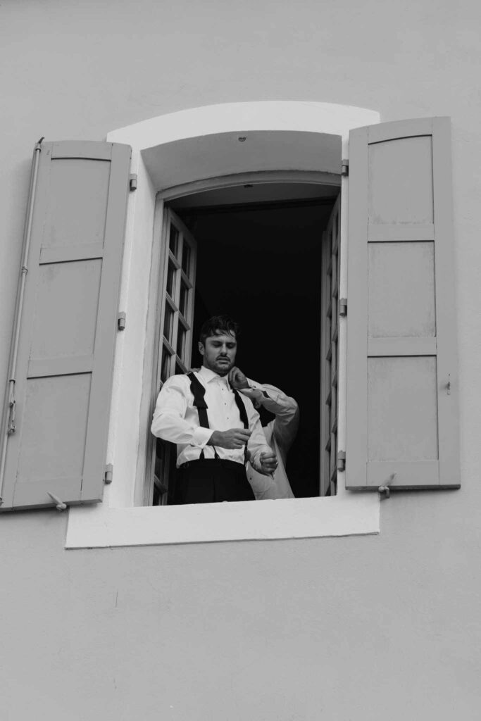 lesCrostes Ingrid groom getting ready assisted by the window black white photo