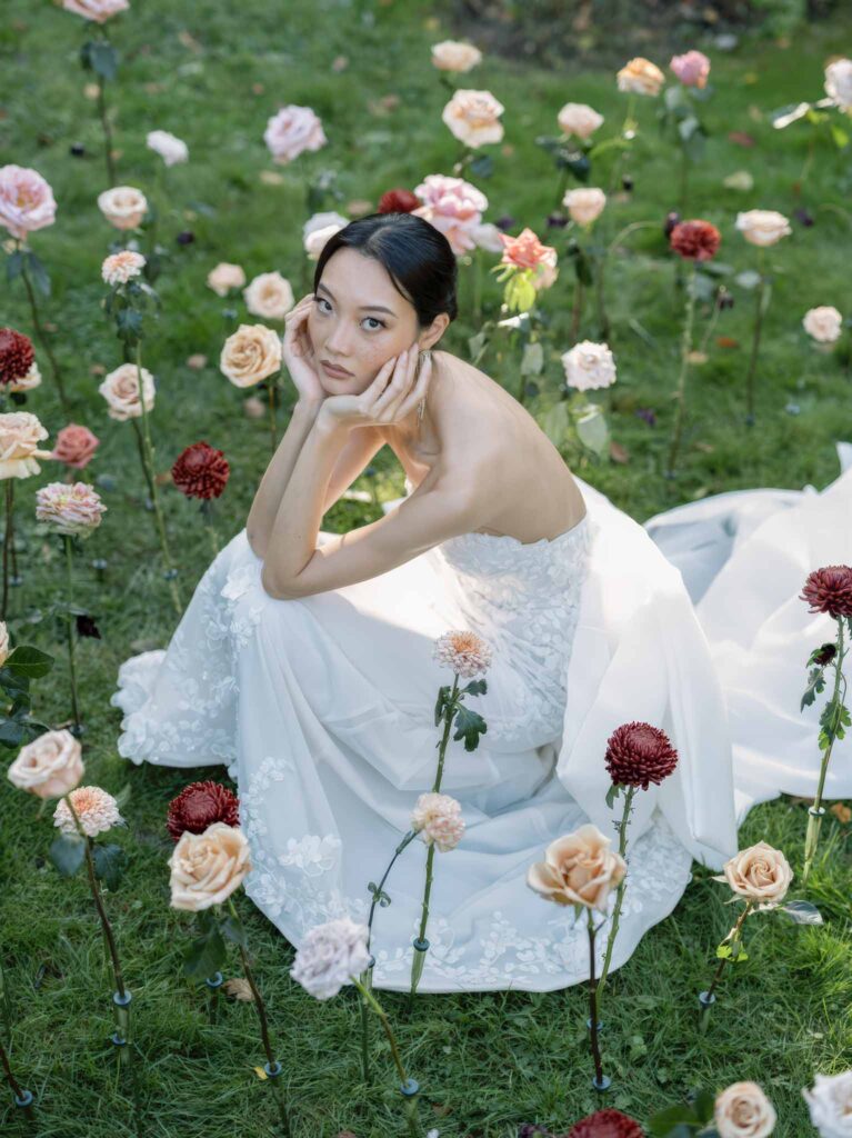 wedding editorial at Manoir de Vacheresses bride sitting hands chin grass flowers around