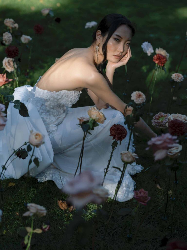 Manoir de Vacheresse Capucine bride sitting hands chin grass flowers around sunset