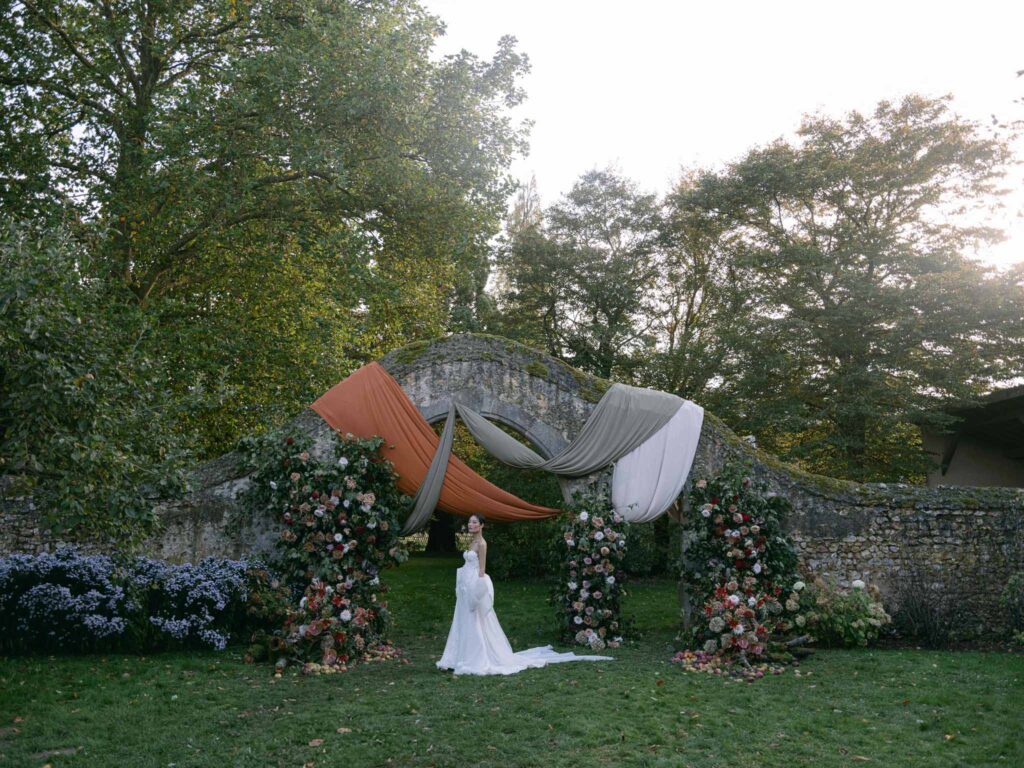 Manoir de Vacheresse Capucine bride standing brick structure background flowers